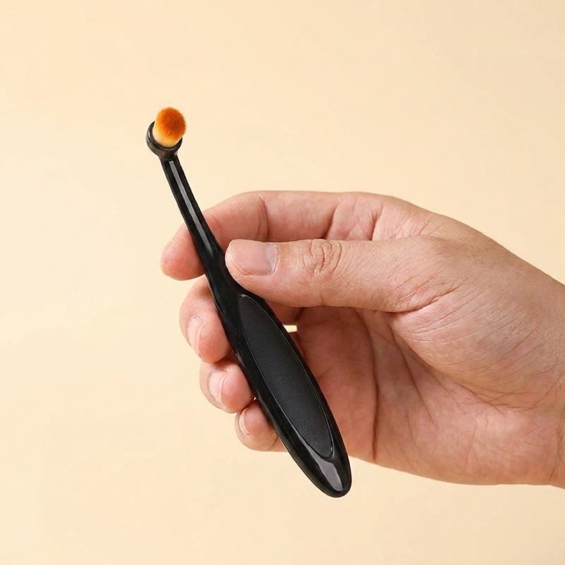 The brush held in hand for scale